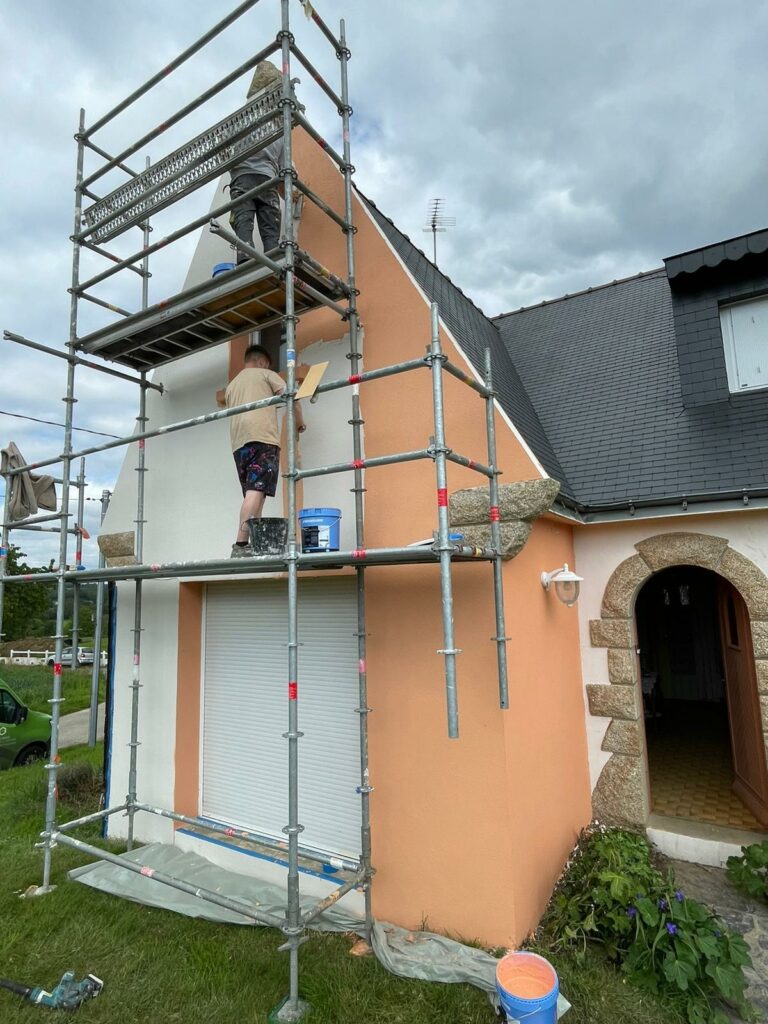 Travaux d'enduit de façade pour protection contre les intempéries sur une maison avec échafaudage